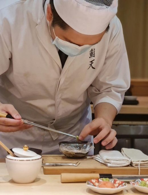 A skilled Japanese chef meticulously prepares sashimi in an intimate restaurant setting.